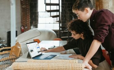 a man and a woman are looking at a laptop